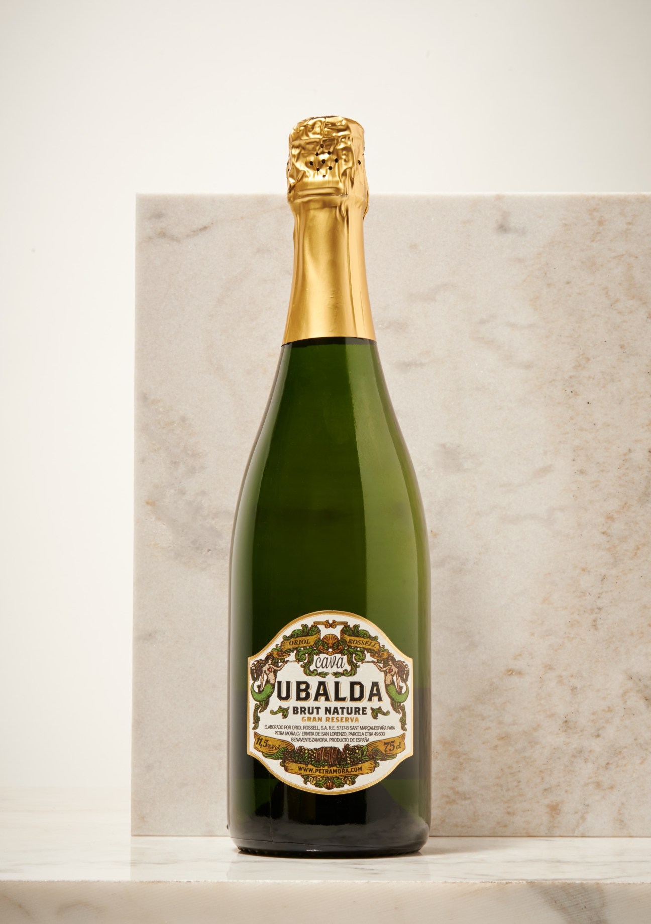 Ubalda Brut Nature Gran Reserva cava bottle with gold foil cap and ornate label against marble background.