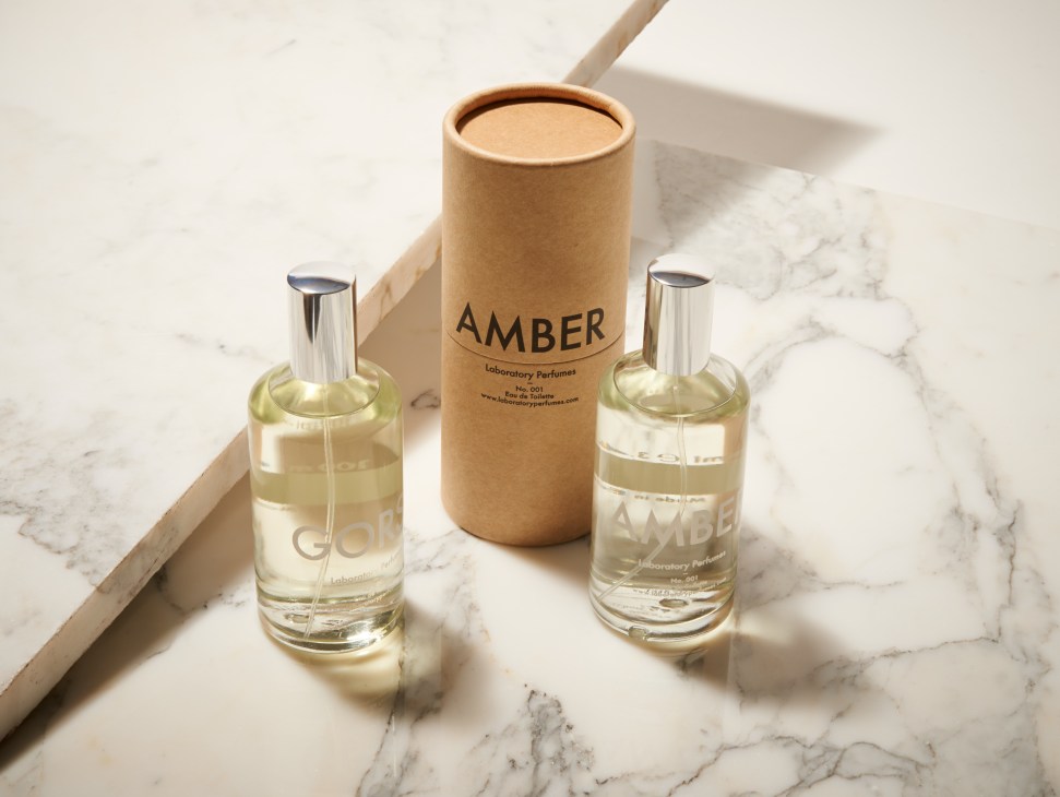 Laboratory Perfumes Amber fragrance with two glass bottles and cardboard tube packaging on marble surface.