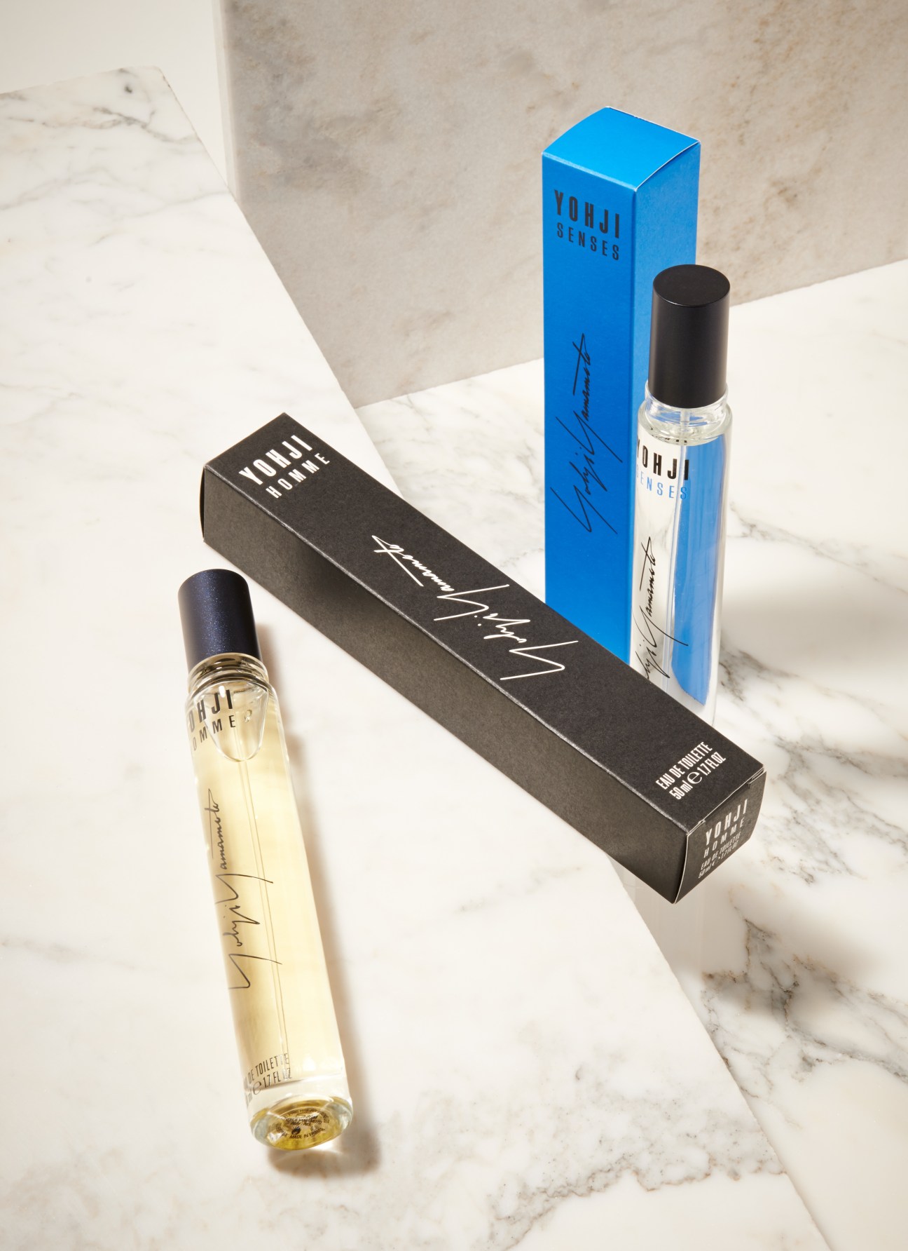 Yohji Yamamoto fragrances displayed on marble surface with blue and black packaging.
