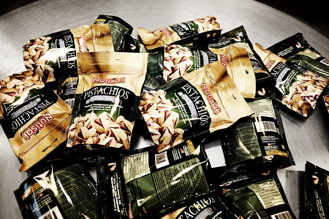 Nutisal pistachio packages in cream and black packaging arranged on a grey surface.