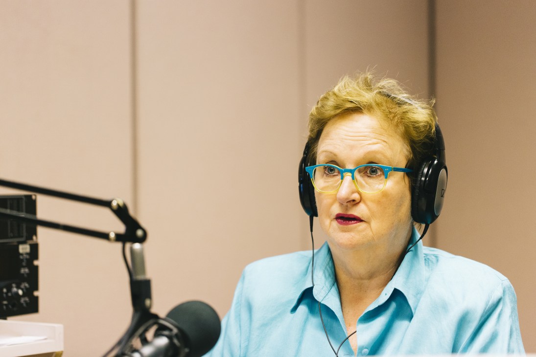 Amanda Vanstone wearing headphones and glasses in a radio studio with microphone