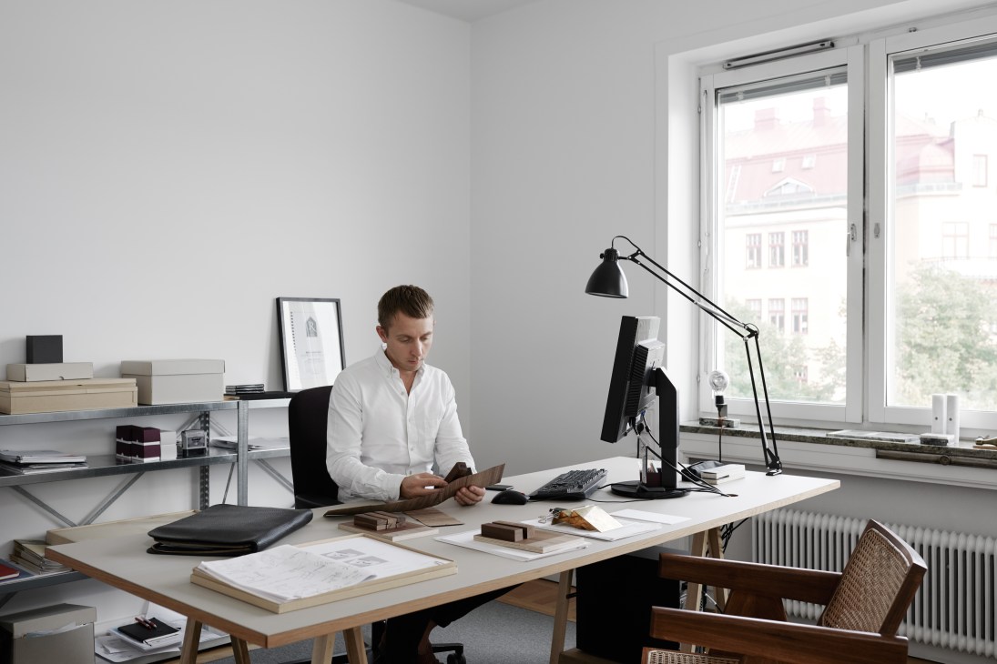Andreas Martin-Löf sits at a wooden desk in his minimalist Stockholm office, working on his phone