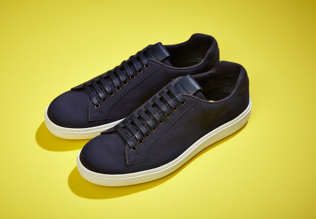 Pair of Church's navy canvas sneakers with white sole on yellow background.