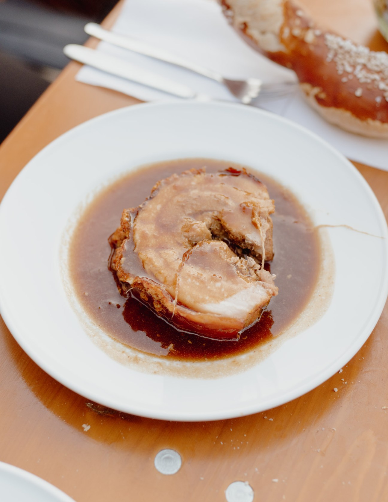 Sliced meat in brown gravy served on a white plate at a Bavarian beer garden.