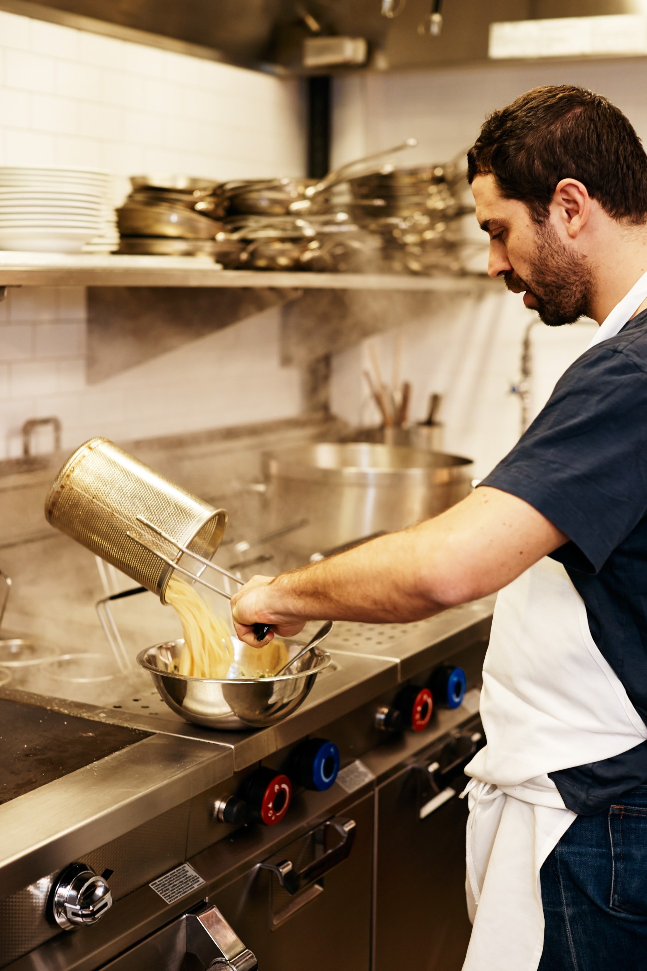 Chef straining pasta in professional kitchen at Café Altro Paradiso.