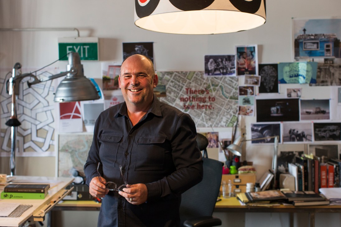 Charlie Nott in his studio, surrounded by architectural drawings and design references on the walls.