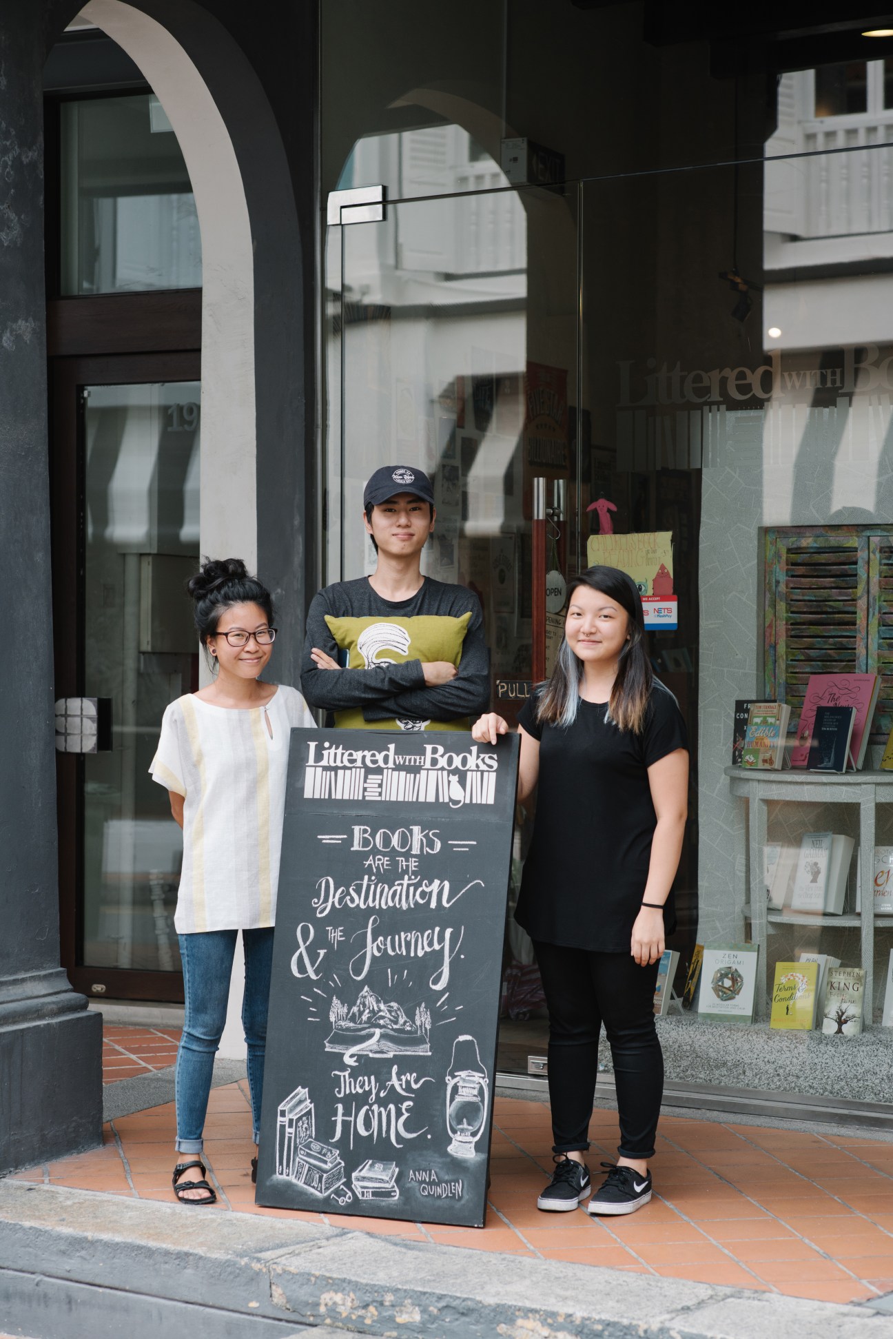 Three staff members standing outside Littered with Books bookshop in Singapore's Duxton Hill neighbourhood.