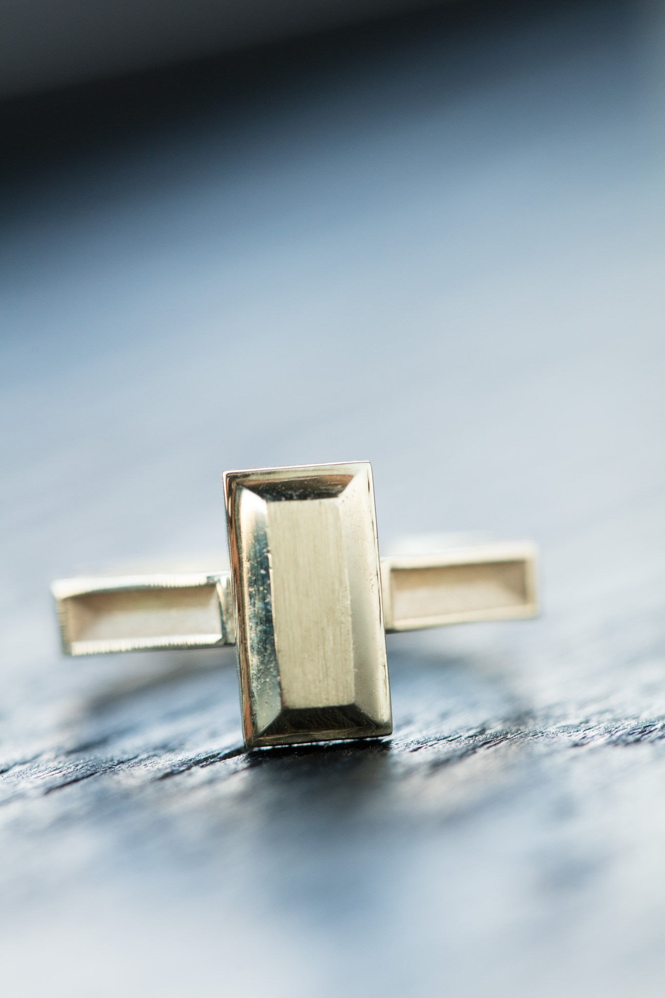 Gold Hunt Amor ring with rectangular geometric design resting on textured wooden surface