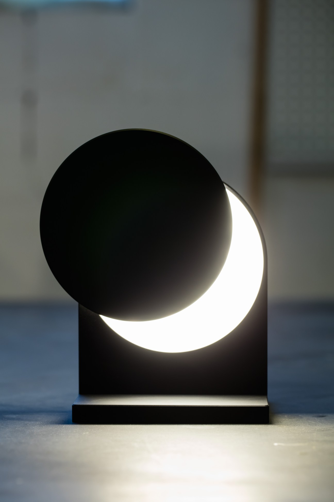 Black sculptural table lamp with overlapping circular elements creating dramatic lighting