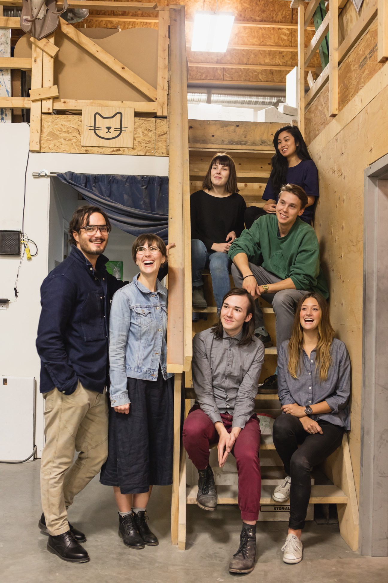 Matt and Shawna Heide and their Concrete Cat team posing on wooden stairs in their workshop