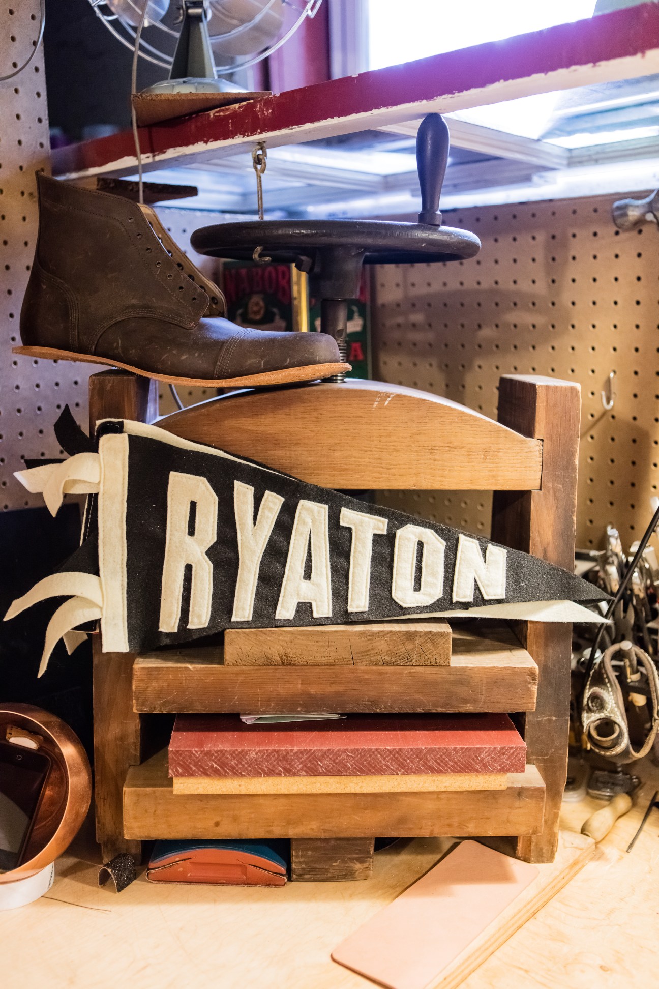 Leather boot on wooden press with Ryaton pennant banner in basement workshop