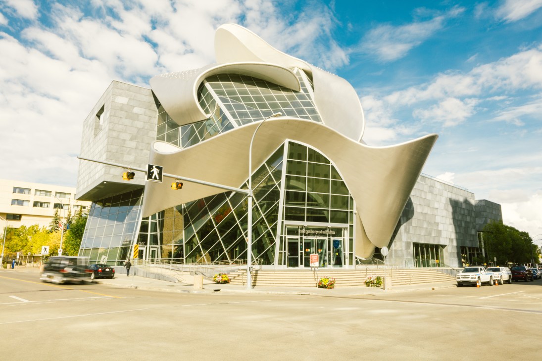Modern Art Gallery of Alberta building with curved white facade and glass windows against blue sky