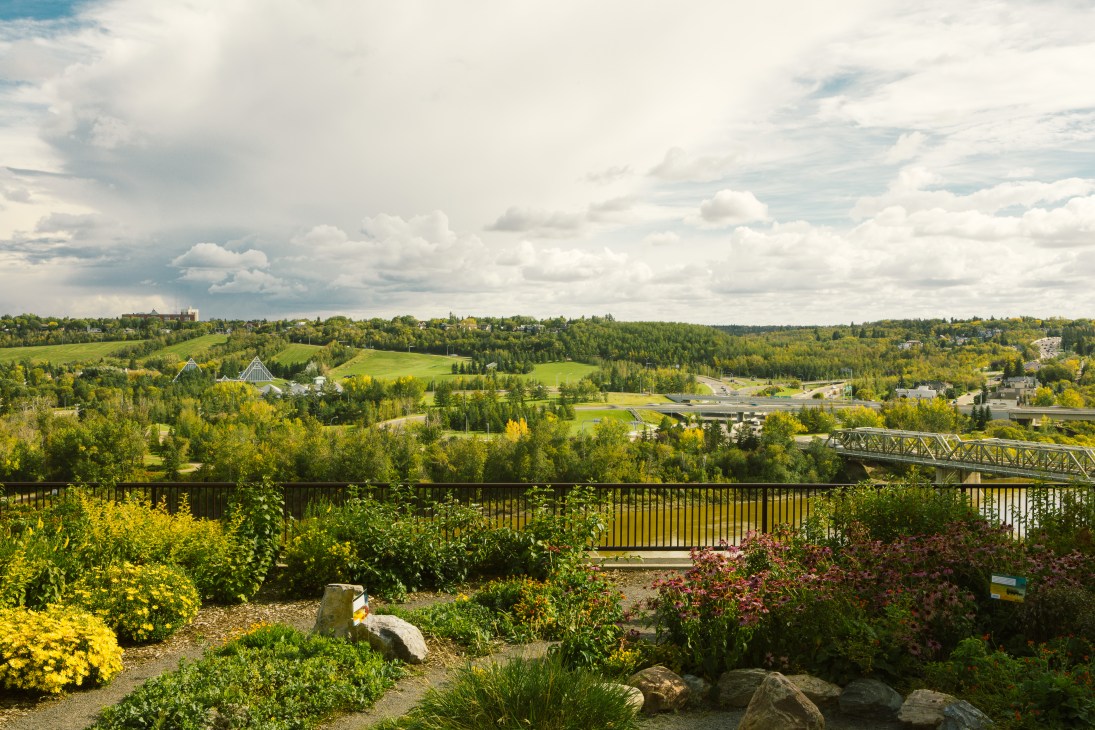 Aerial view of Edmonton's North Saskatchewan River valley with green parkland and a bridge crossing the river