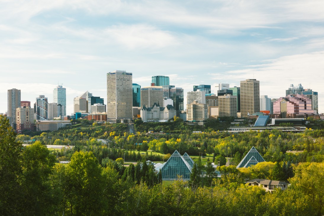 Edmonton skyline with downtown towers and glass pyramids in foreground surrounded by lush green parkland