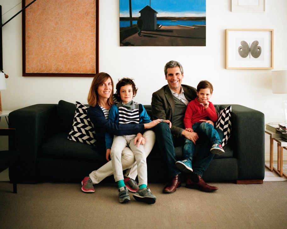 Alejandra, Iván and their two sons Ignacio and Mario Lequerica sit together on a dark sofa in their living room.
