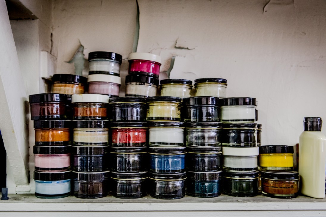 Assorted jars of Famaco shoe cream in various colors arranged on a shelf.