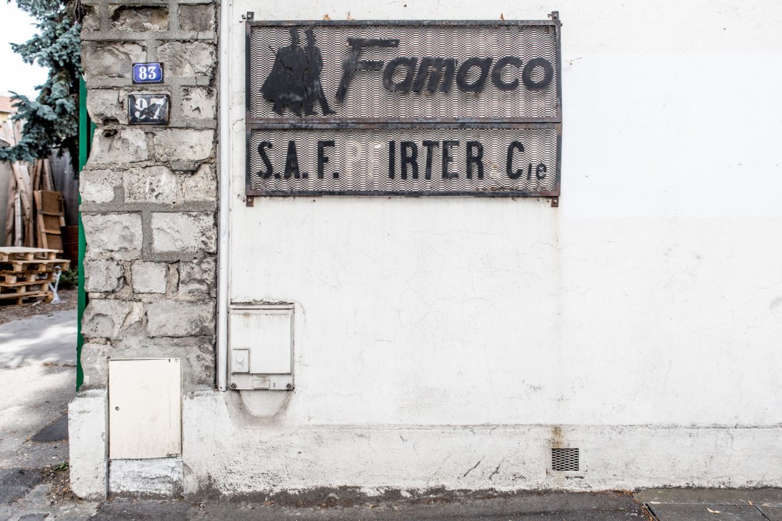 Famaco shoe polish factory entrance with metal signage on a weathered stone building.