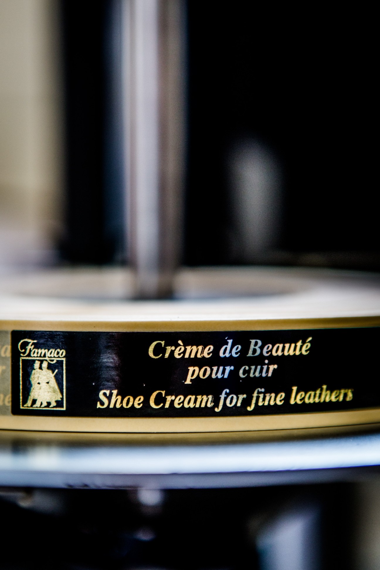 Close-up of a Famaco shoe cream jar label showing the brand logo and product name in gold text on black.