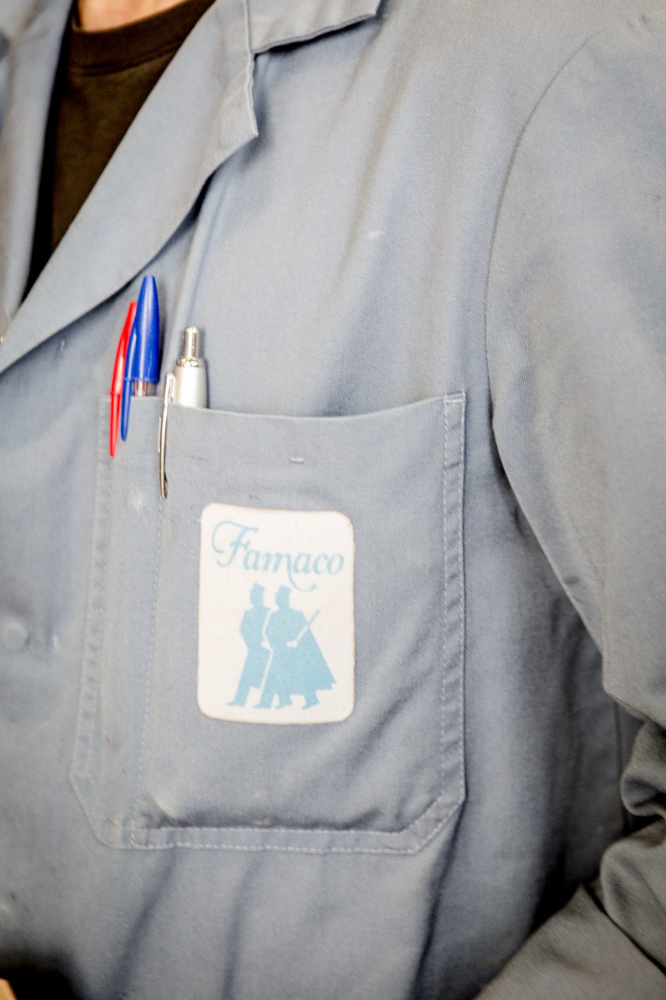 Close-up of Famaco worker overalls pocket with branded sticker and pens