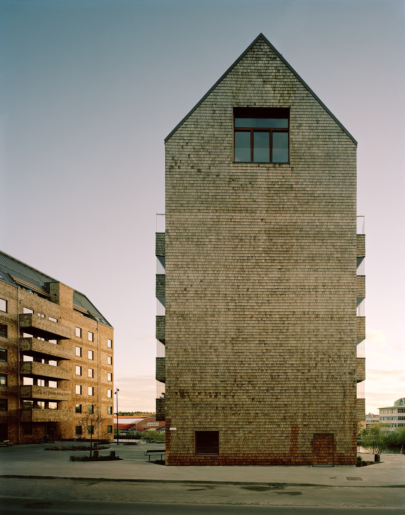 Wooden tower building with cedar-clad facade and large windows against evening sky.