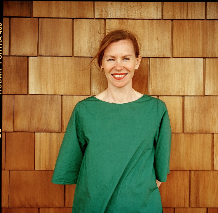 Sandra Frank, marketing manager at Folkhem, smiling in front of a cedar wood facade.