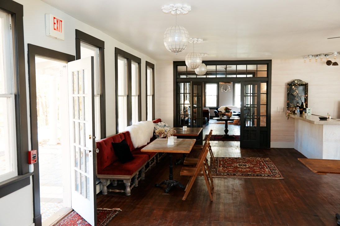 Foxfire Mountain House interior with red velvet sofa, wooden tables, and globe pendant lights.