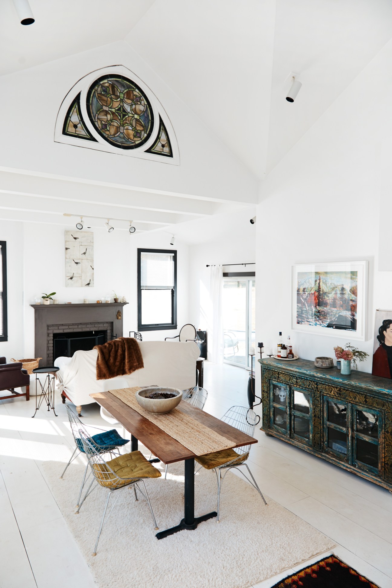 Foxfire Mountain House interior with modern dining setup, fireplace, and large window overlooking landscape.