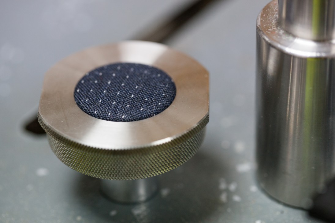 Close-up of Hainsworth Eco-Dry fabric sample mounted on metal testing equipment.