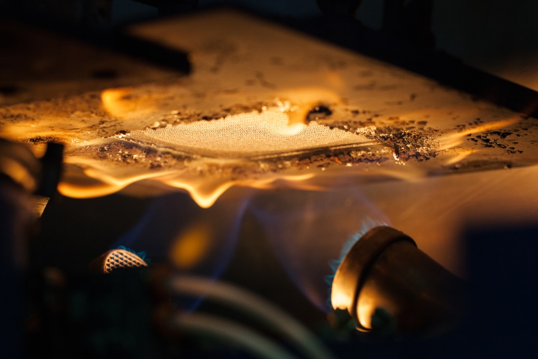Close-up of fabric undergoing thermal testing with intense heat exposure creating glowing effects