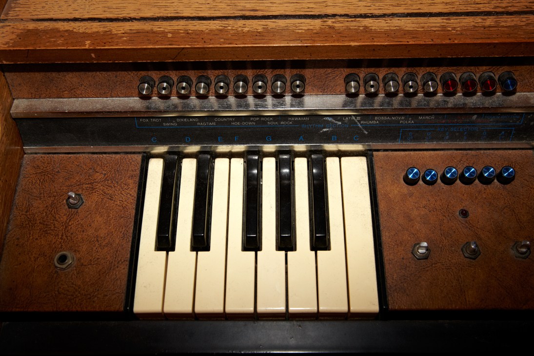 Vintage synthesizer with cream keys, wood panel, and preset buttons for music production.