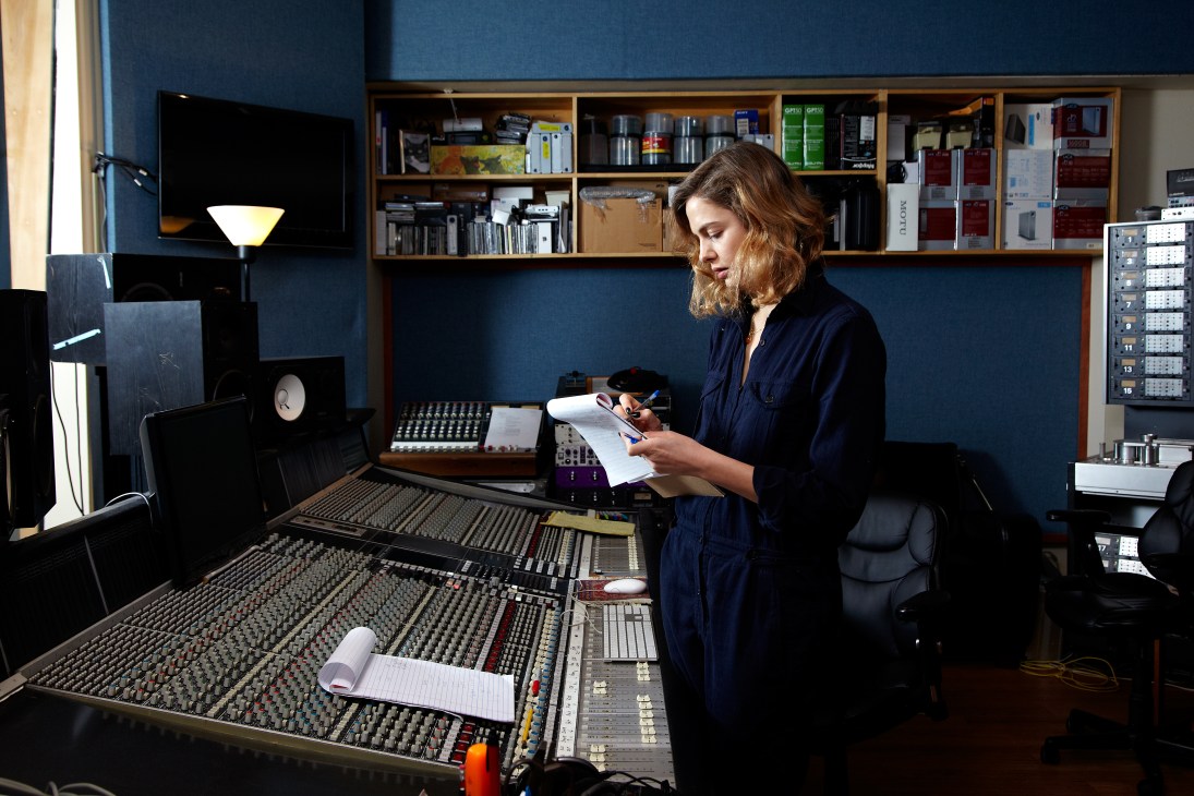 Hannah Cohen writing notes at a mixing console in a Manhattan recording studio.