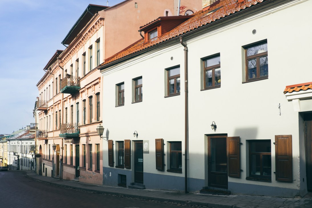 Historic buildings along Uzupio gatve in Vilnius's Uzupis neighbourhood, with Sweet Root restaurant at street level.