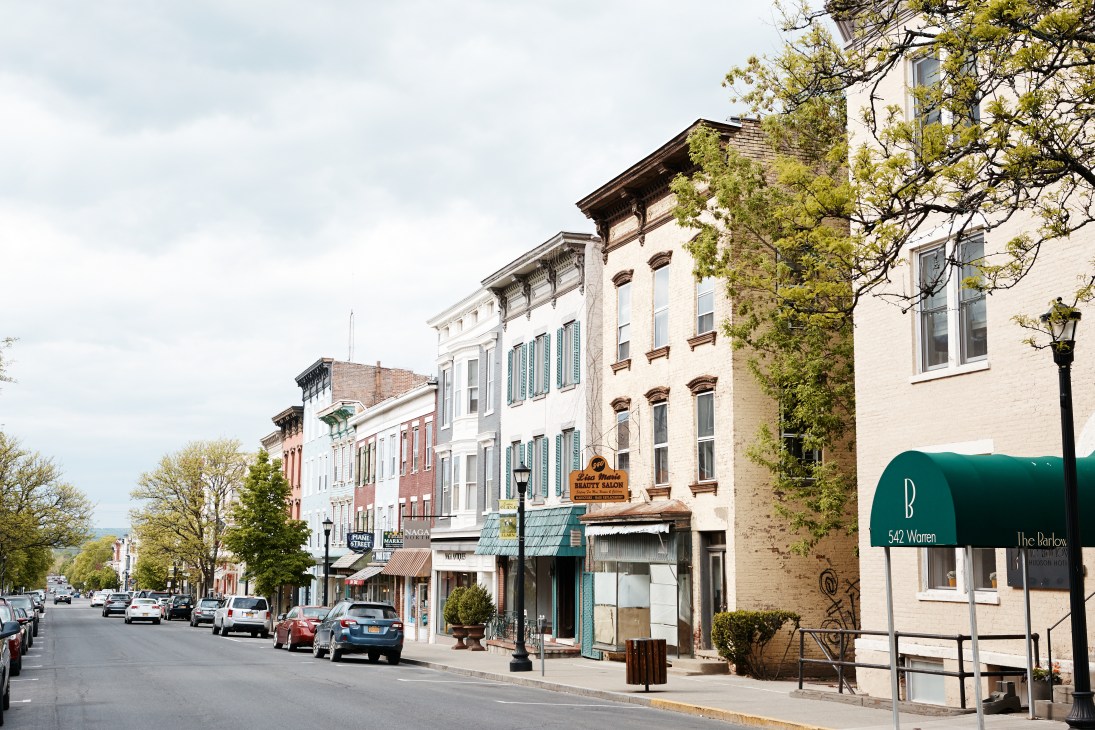 Warren Street in Hudson with historic multi-story buildings, storefronts, and a green awning for a business at 542 Warren.