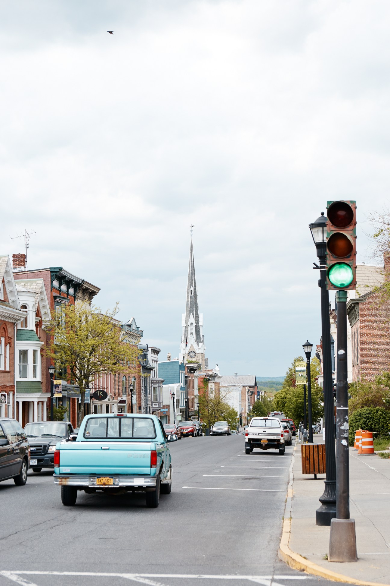 Warren Street in Hudson with a green traffic light, vintage turquoise truck, and church steeple in the distance.
