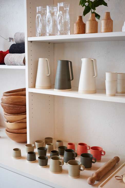White shelving unit displaying ceramic vessels, wooden bowls, glassware, textiles and wooden utensils from Makers & Brothers.