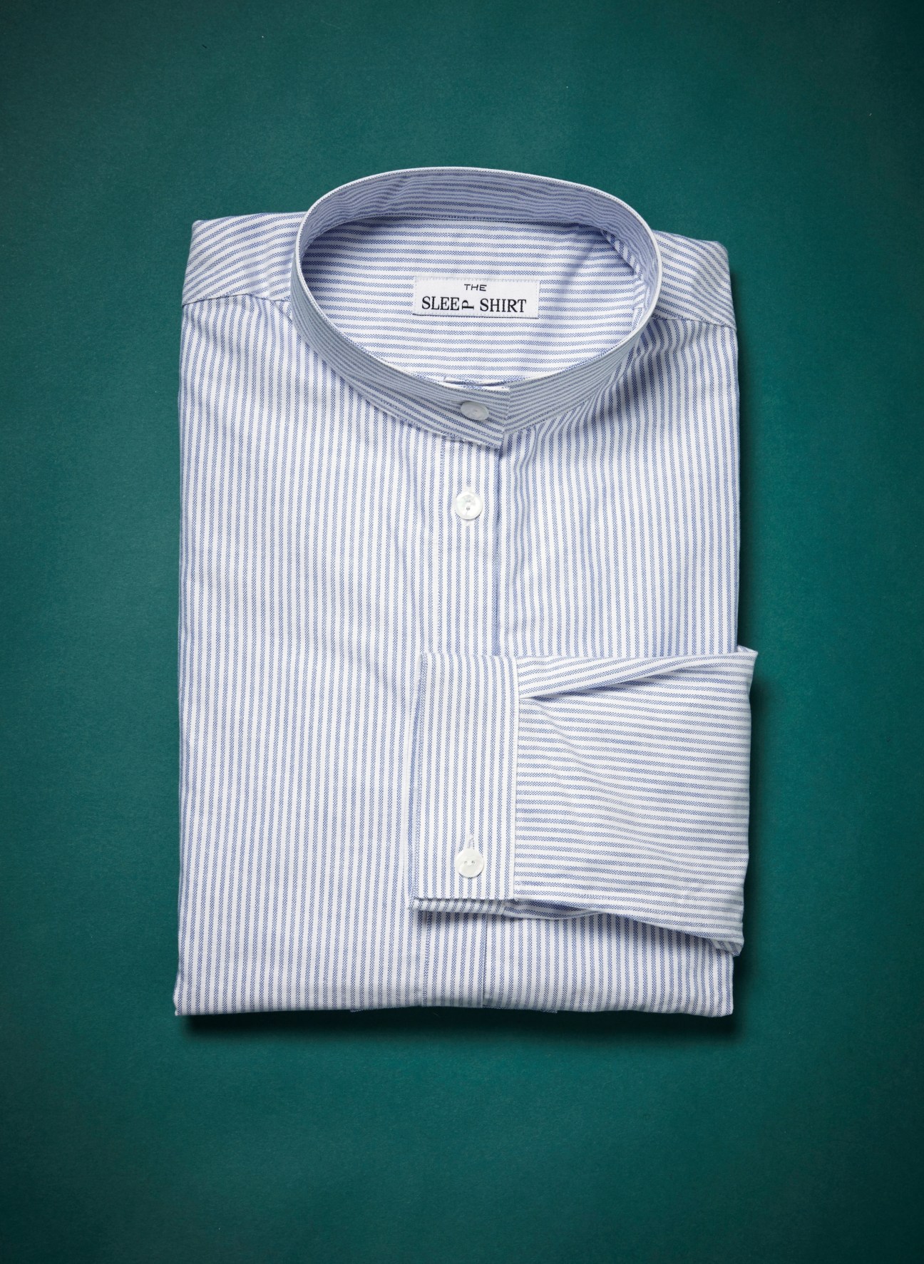 Folded blue and white striped sleep shirt with The Sleep Shirt label on teal background.