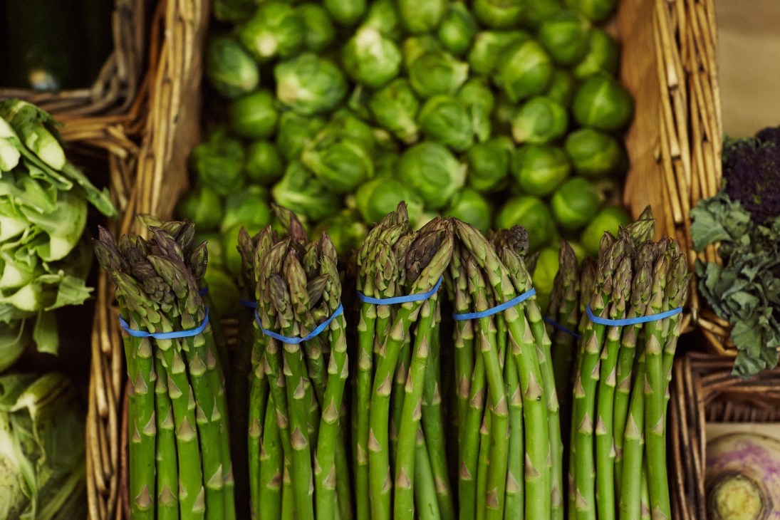 Fresh green asparagus bunches tied with blue bands at a market display.