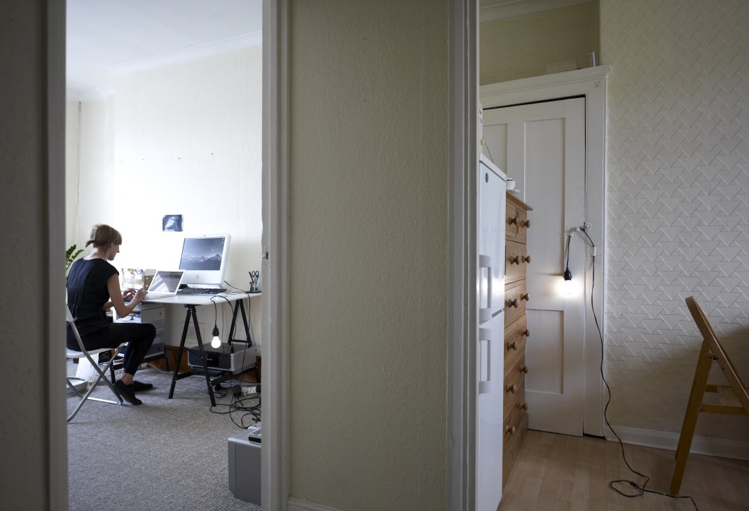 Artist Katie Paterson working at her clean white desk in her home office, surrounded by computers and minimalist workspace.