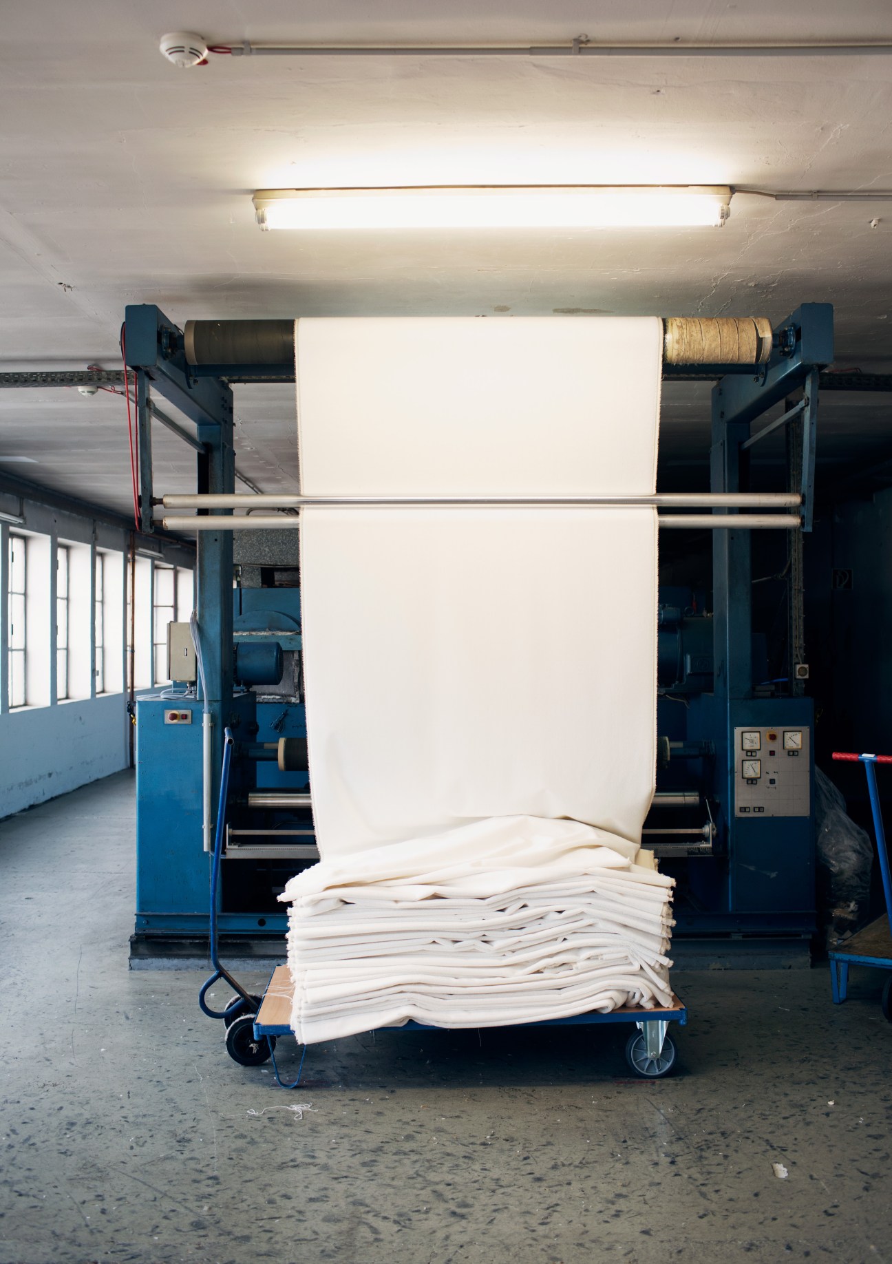 Industrial fabric inspection machine with white textile being checked under bright light at Steiff Schulte factory.
