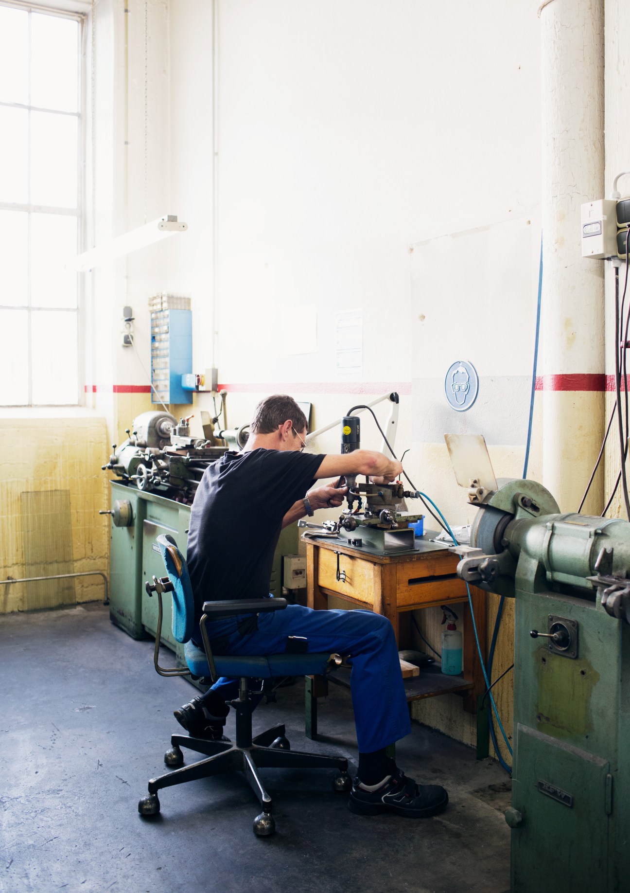 Worker performing manual finishing work on textile machinery at Steiff Schulte factory.