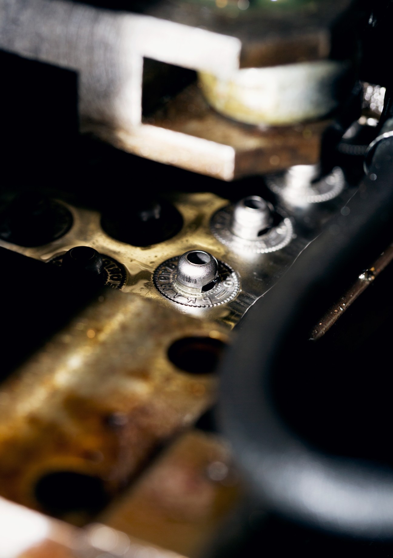 Close-up of brass snap fastener buttons during quality control inspection at Prym factory.