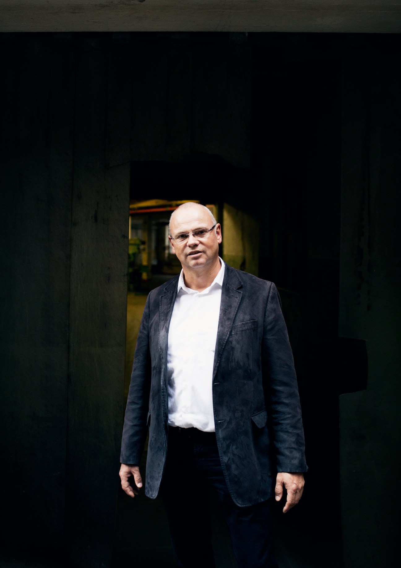 Axel Wirthmüller, vice-president of operations at Prym, stands in an industrial factory corridor wearing glasses and a dark blazer.