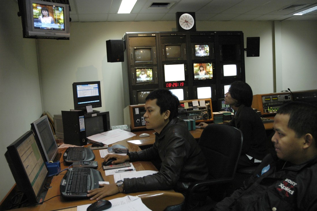 Broadcast operators working at control desks during a live television broadcast at Jak TV in Jakarta.