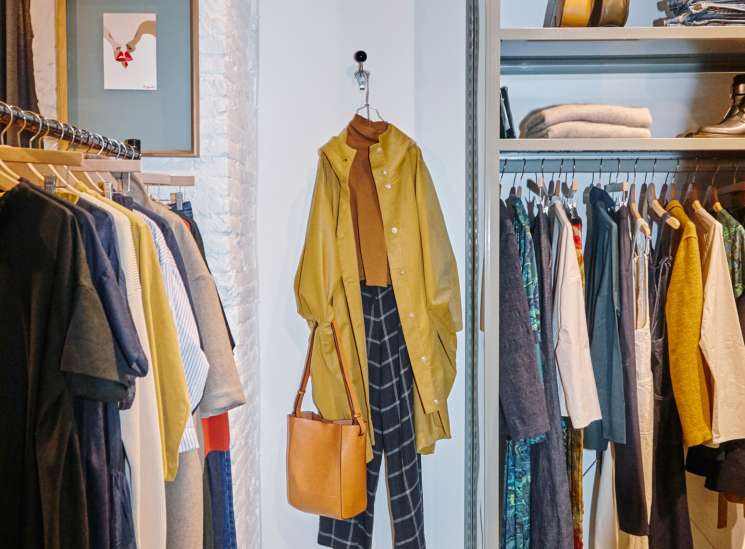 Rendez-vous womenswear store interior showing styled outfit display with yellow coat, plaid trousers and tan bag on mannequin.