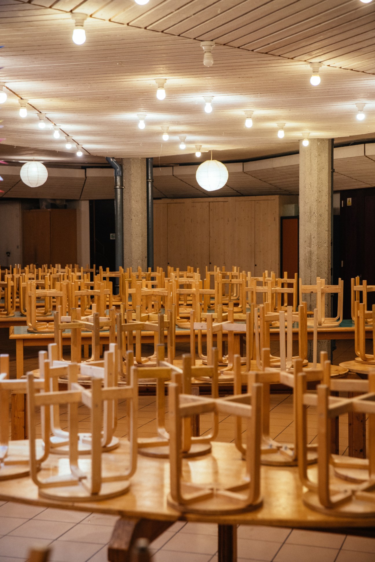 School cafeteria with rows of wooden chairs and illuminated ceiling in Geneva.