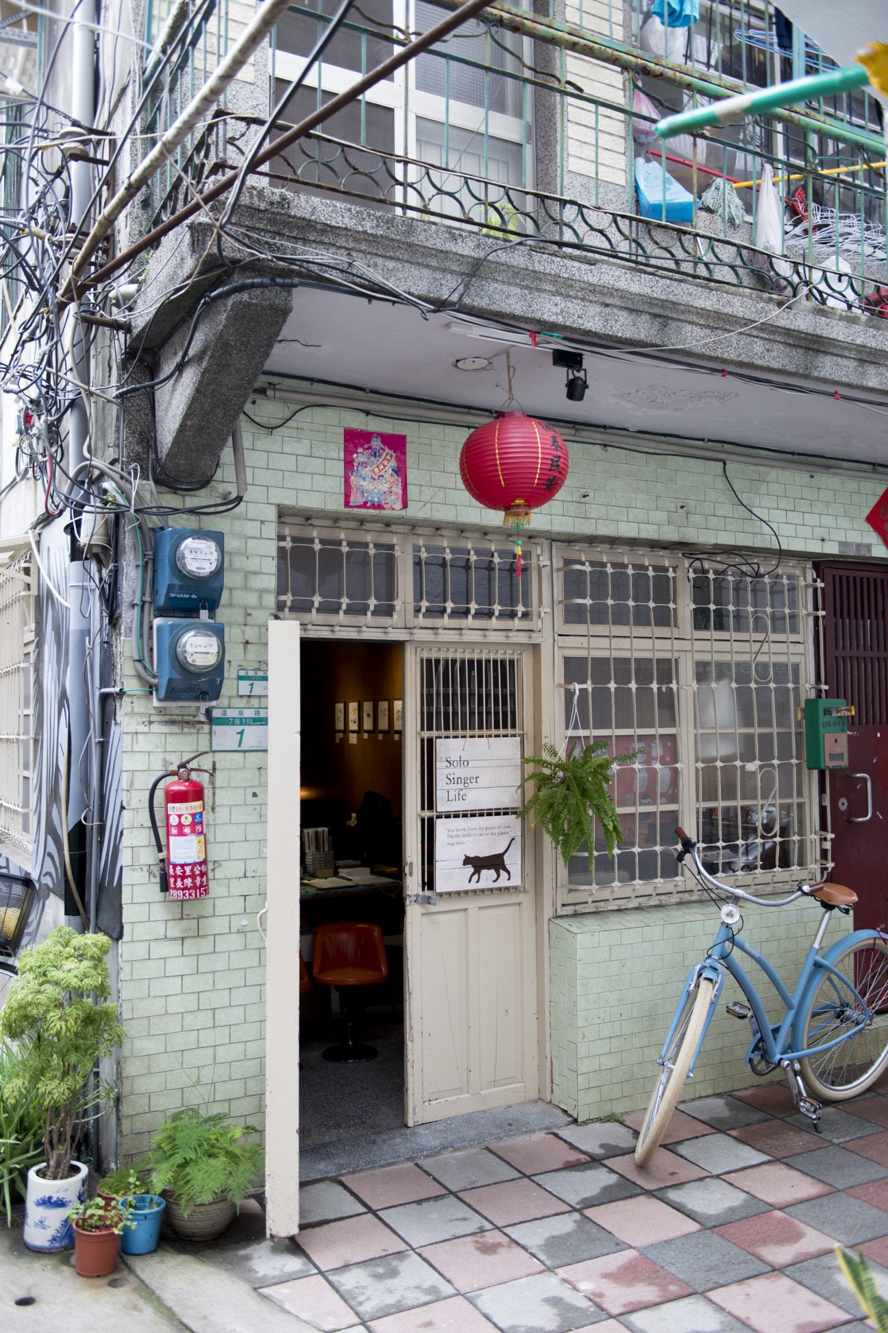 Storefront of Solo Singer Life café with red lantern, bicycle parked outside, and tangled power lines above