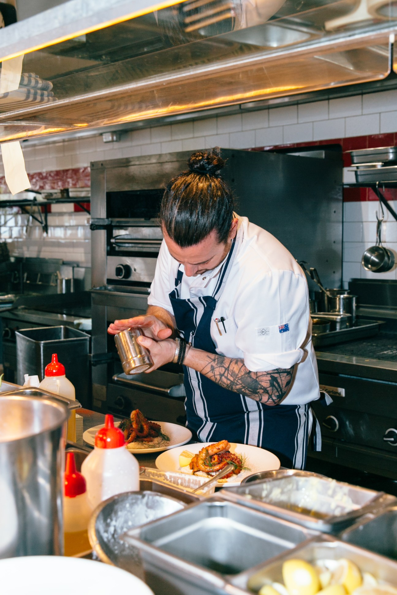 Chef Jordan Toft prepares food in a professional kitchen at Coogee Pavilion.