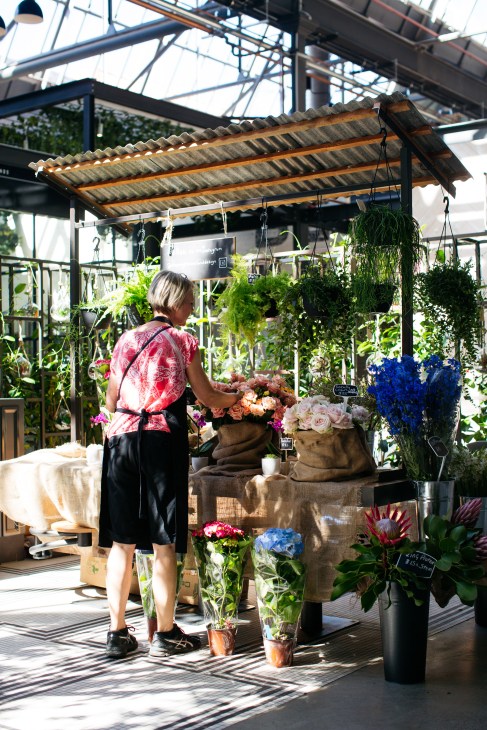 Florist arranging flowers at Thorny Roses stall inside Tramsheds market hall in Sydney.