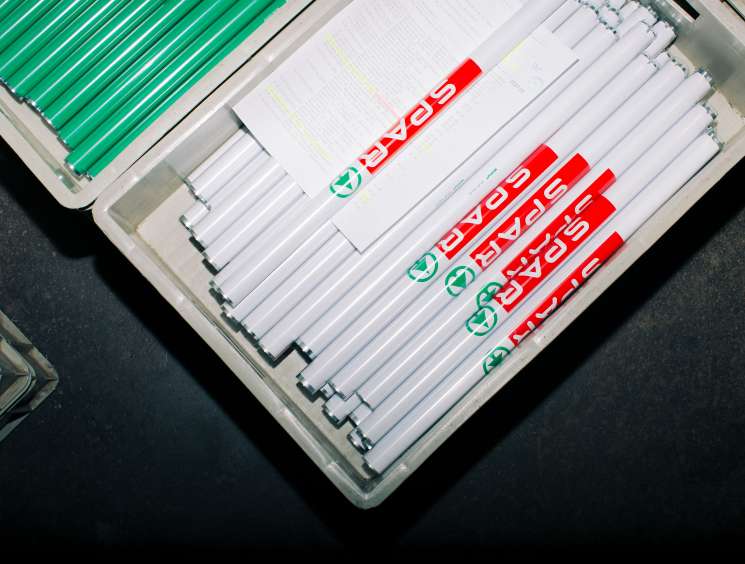 Close-up of shopping trolley handlebar components with Spar branding displayed on factory floor.