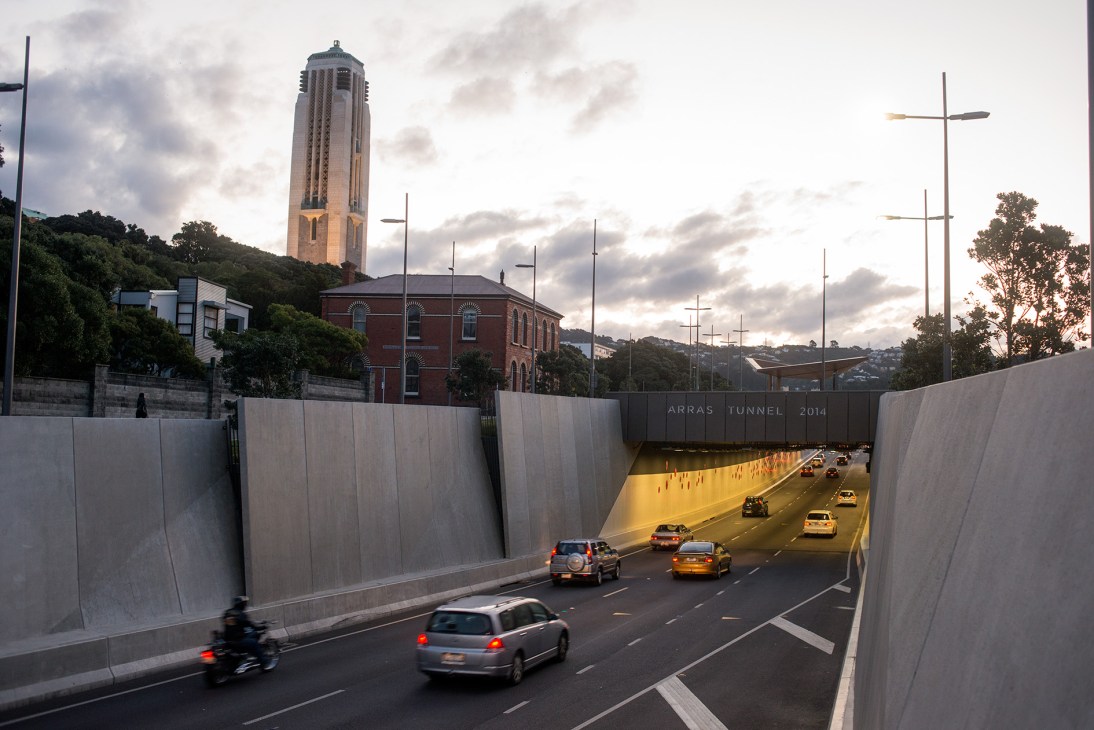 Underground tunnel with traffic below crosses monument and war memorial carillon tower on hillside.